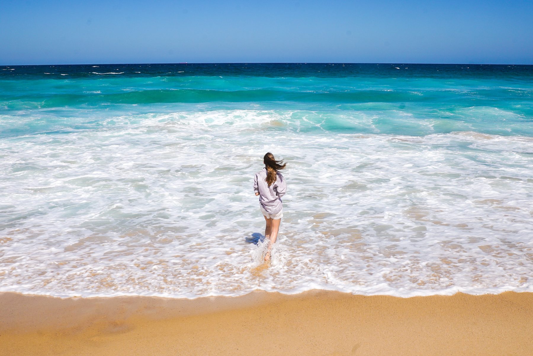 A woman walking into the sea on a beach